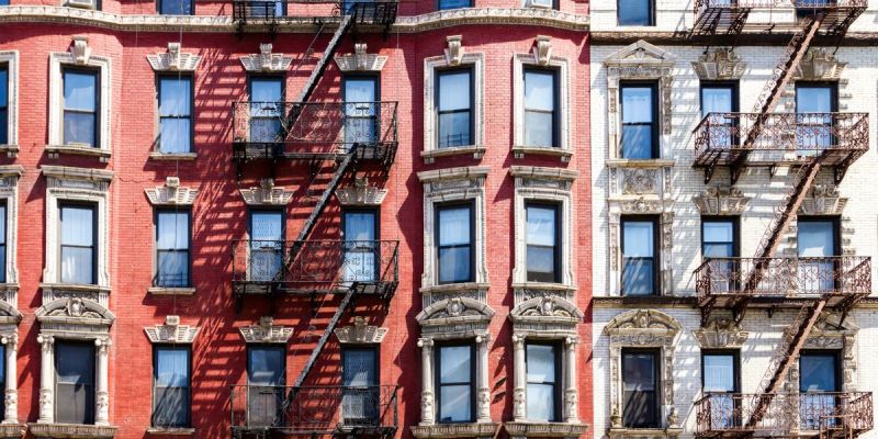 Classic New York City apartment buildings with fire escapes in a walkable residential neighborhood