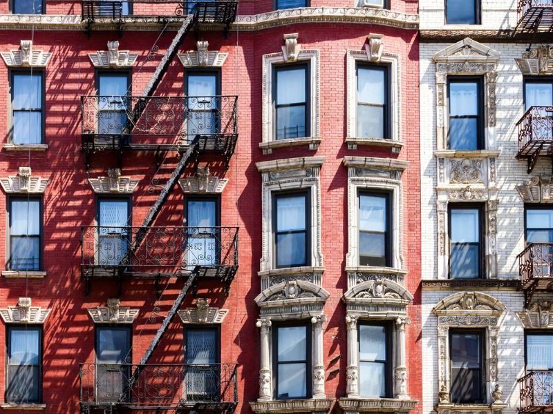 Classic New York City apartment buildings with fire escapes in a walkable residential neighborhood