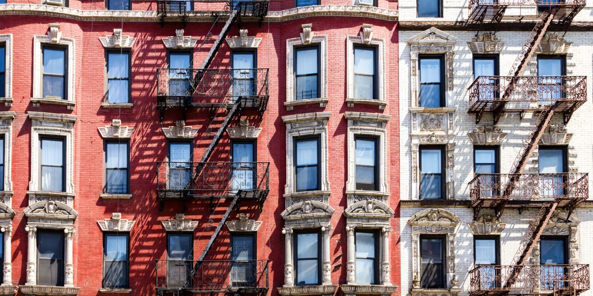 Classic New York City apartment buildings with fire escapes in a walkable residential neighborhood