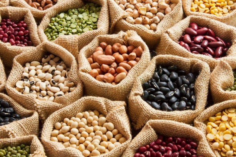Variety of dried beans and legumes in burlap sacks.