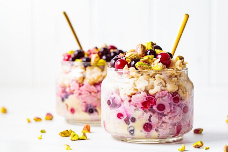 Two jars of overnight oats topped with berries and pistachios.