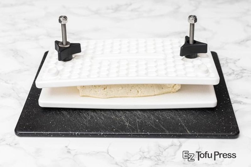 EZ Tofu Press pressing tofu between two plastic plates on a kitchen counter