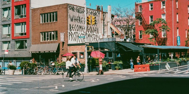 Cyclist riding through a Williamsburg Brooklyn street with cafes and local businesses